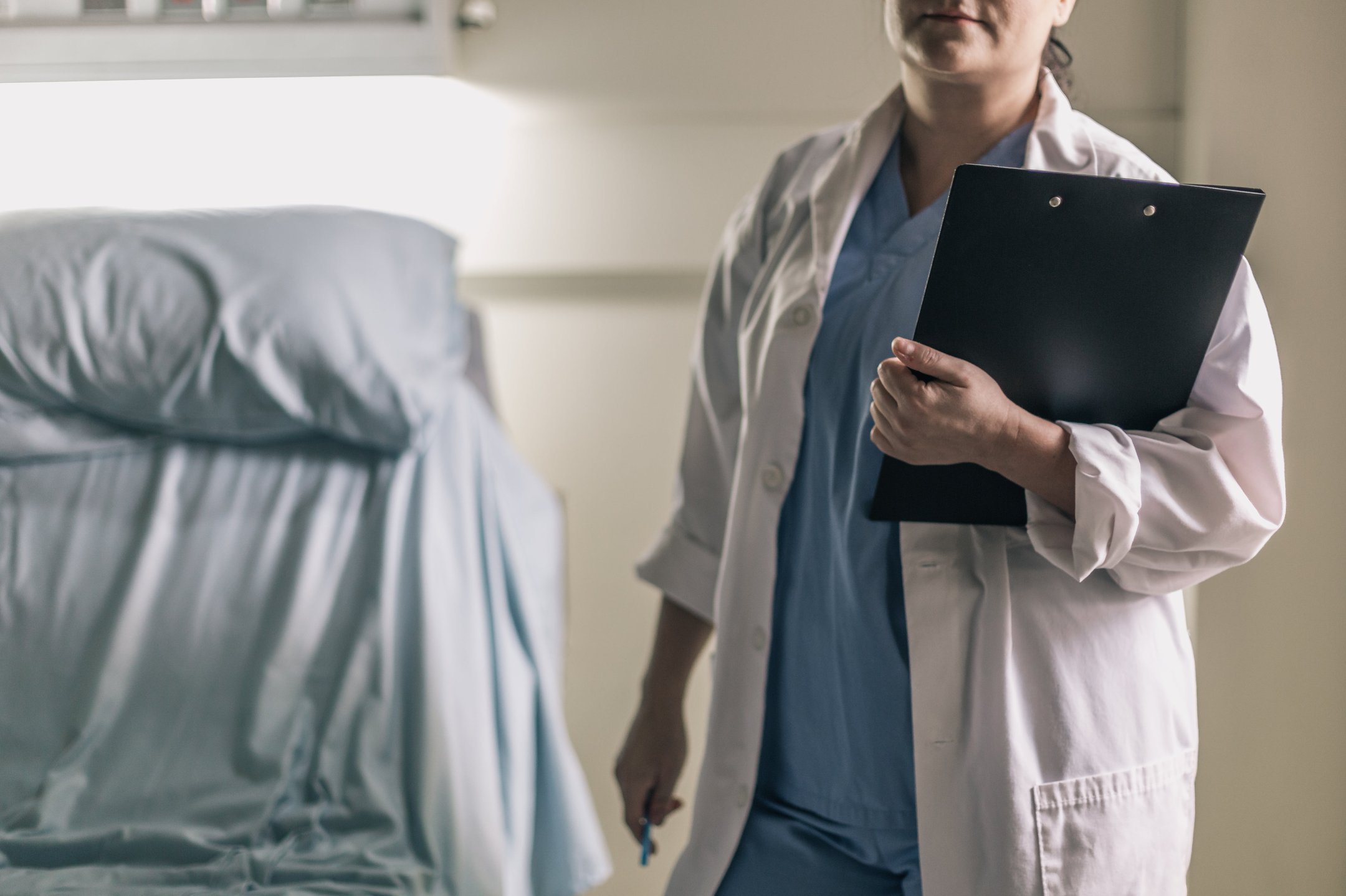 medical-professional-in-scrubs-holding-clipboard-and-pen